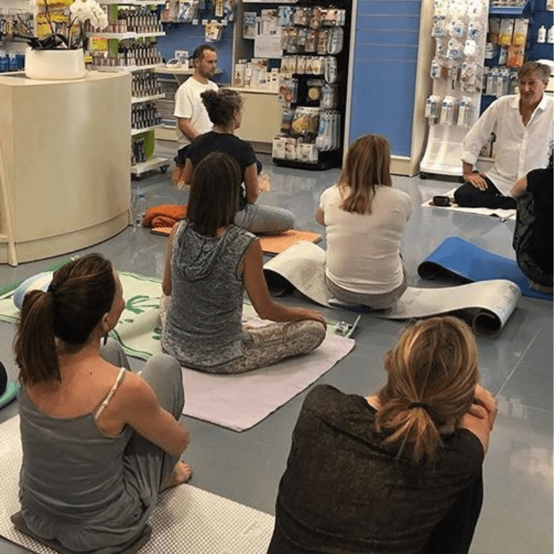 Un maestro meditando al frente de un grupo de meditadores en una sala espaciosa y serena.